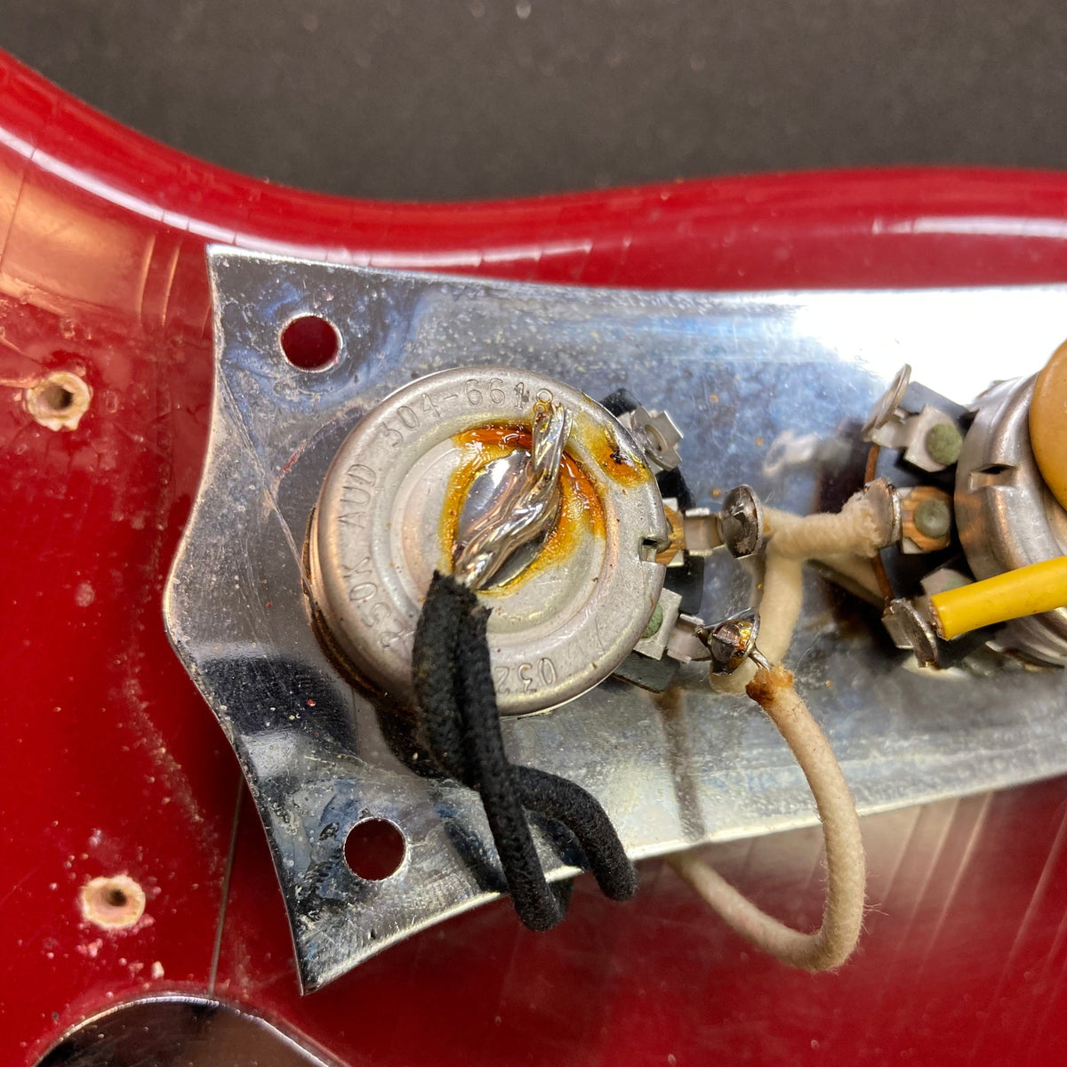 Close-up of a 1966 Fender Duo-Sonic II guitar with visible checking and blemishes on the Dakota Red finish.