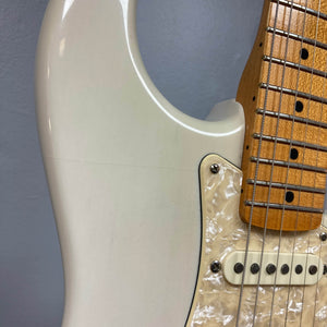 Close-up of a 2006 Fender Eric Johnson Stratocaster guitar body by Fender, featuring strings, pickups, a pearl pickguard, and part of the Maple Fingerboard neck against a gray background.