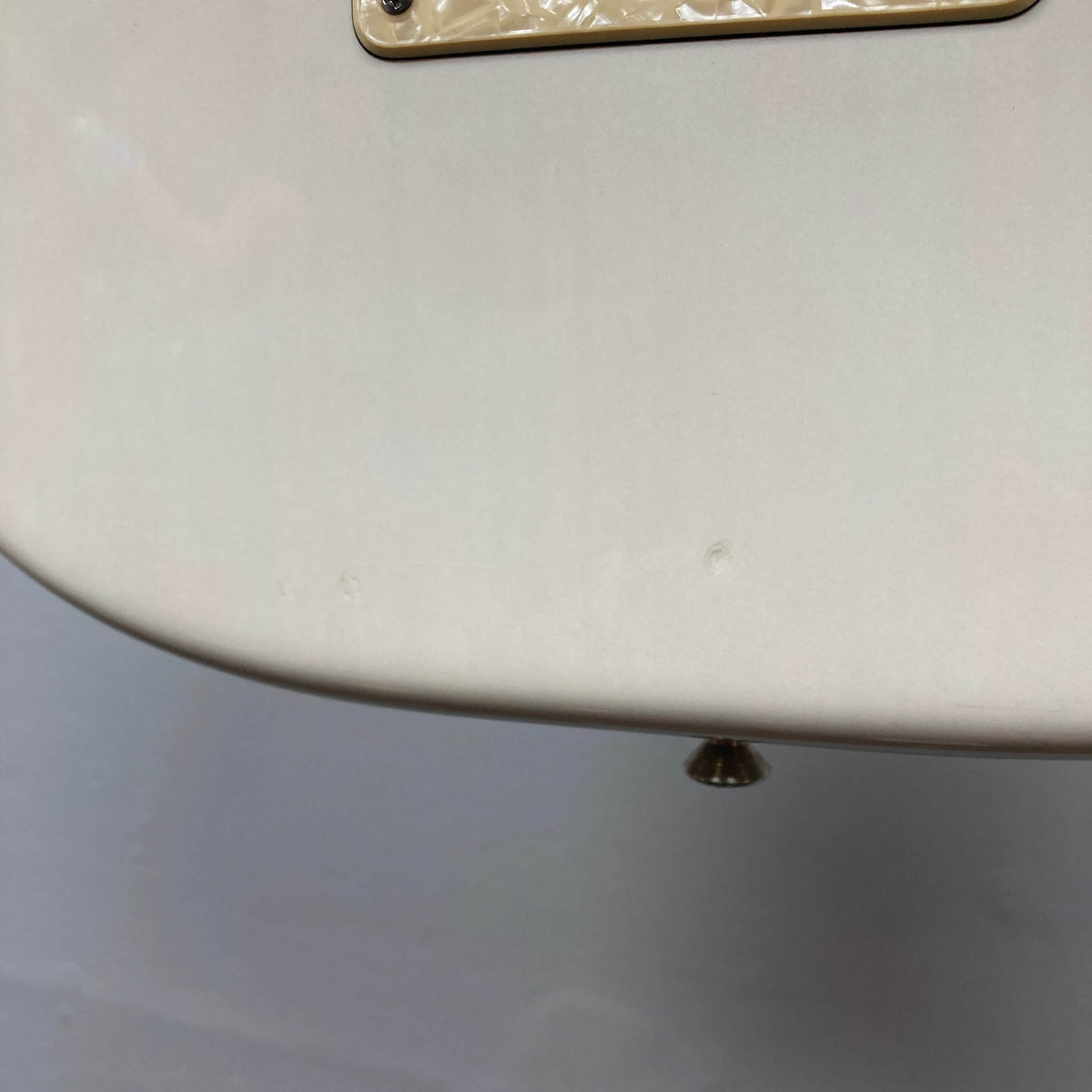 Close-up of a cream-colored 2006 Fender Eric Johnson Stratocaster guitar body by Fender, featuring minor dents, signature details, and a visible strap button at the bottom edge.