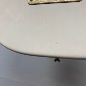 Close-up of a cream-colored 2006 Fender Eric Johnson Stratocaster guitar body by Fender, featuring minor dents, signature details, and a visible strap button at the bottom edge.