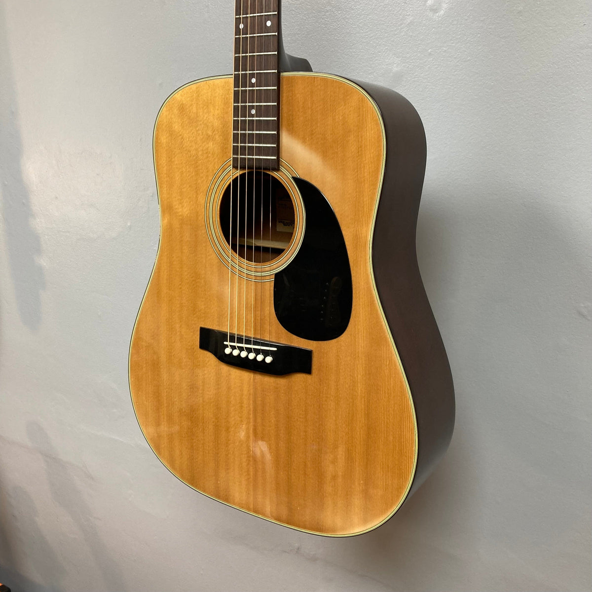 Fender F-35 1972-1981, Natural MIJ guitar on wall, showcasing detailed craftsmanship with visible strings and wood grain.