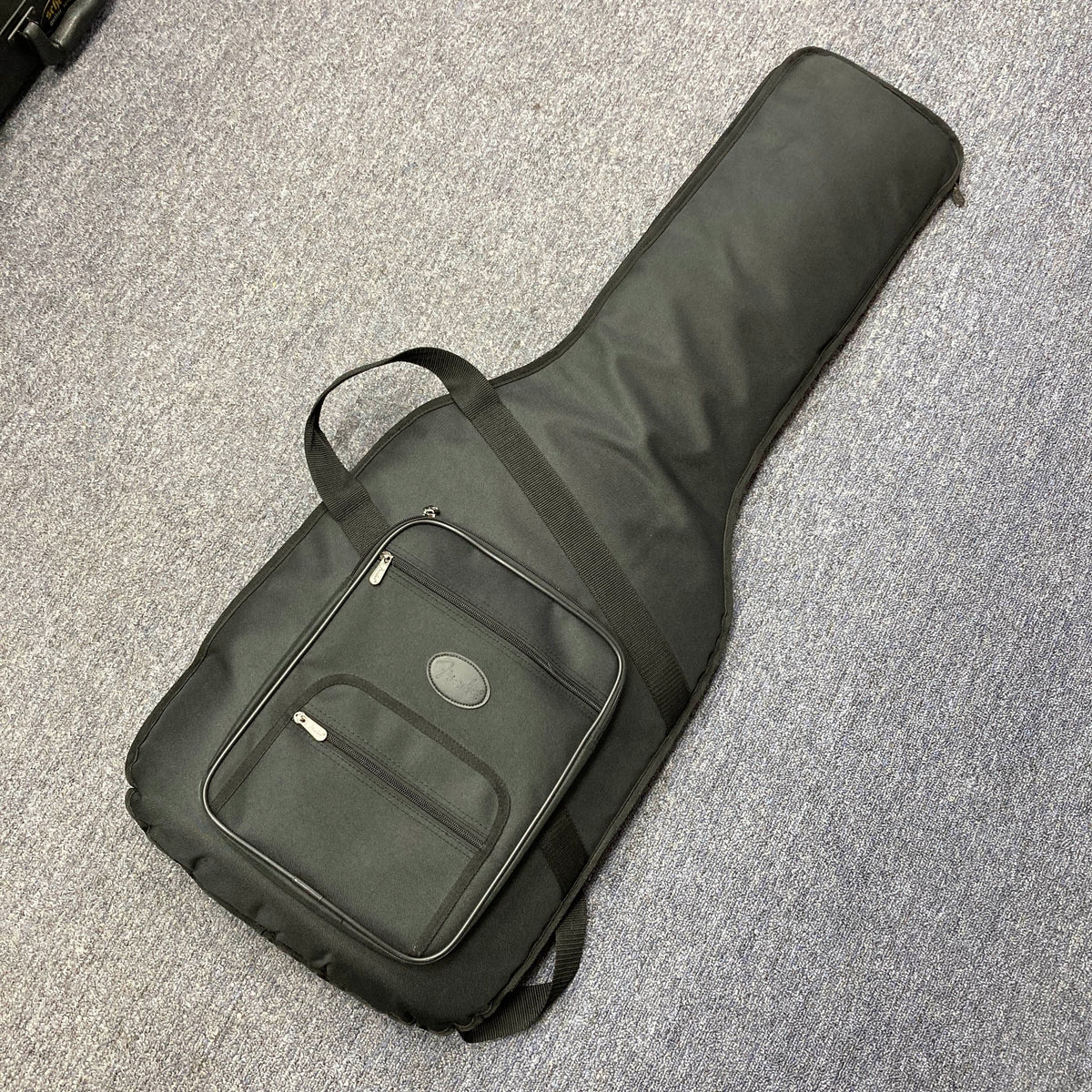A black soft gigbag, ideal for the Fender Heritage '60s Telecaster Custom Made in Japan Sunburst, sits on a gray carpet and features a front zipper pocket.