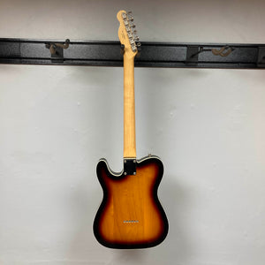 The Fender Heritage '60s Telecaster Custom Made in Japan in Sunburst hangs on a wall rack, back view with a light-colored neck and no visible strings—a classic vintage-style electric guitar. Includes gig bag.