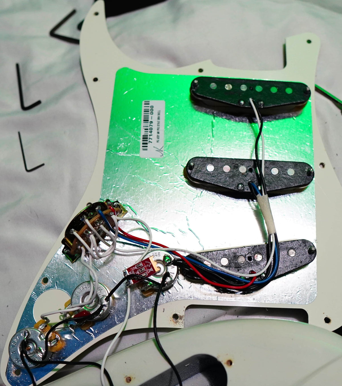 Close-up of a Fender Limited Edition Ash American Professional Stratocaster White Blonde pickguard removed, exposing wiring, three pickups, and detailed electronics.