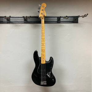 Fender Player II Jazz Bass Black Refurb hanging on a wall, showcasing its contoured alder body and modern C neck profile with satin finish.