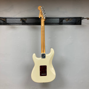 Fender Player Plus Stratocaster Olympic Pearl on black shelf, showcasing its sleek design and expert craftsmanship, includes gig bag.