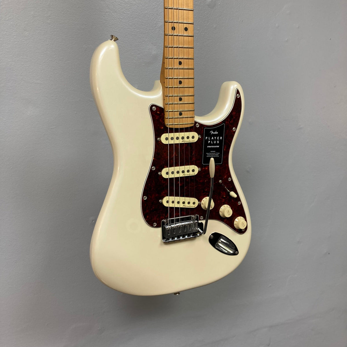 Fender Player Plus Stratocaster Olympic Pearl electric guitar with gig bag, featuring a white body, brown hardware, and a close-up of the guitar neck and bridge.