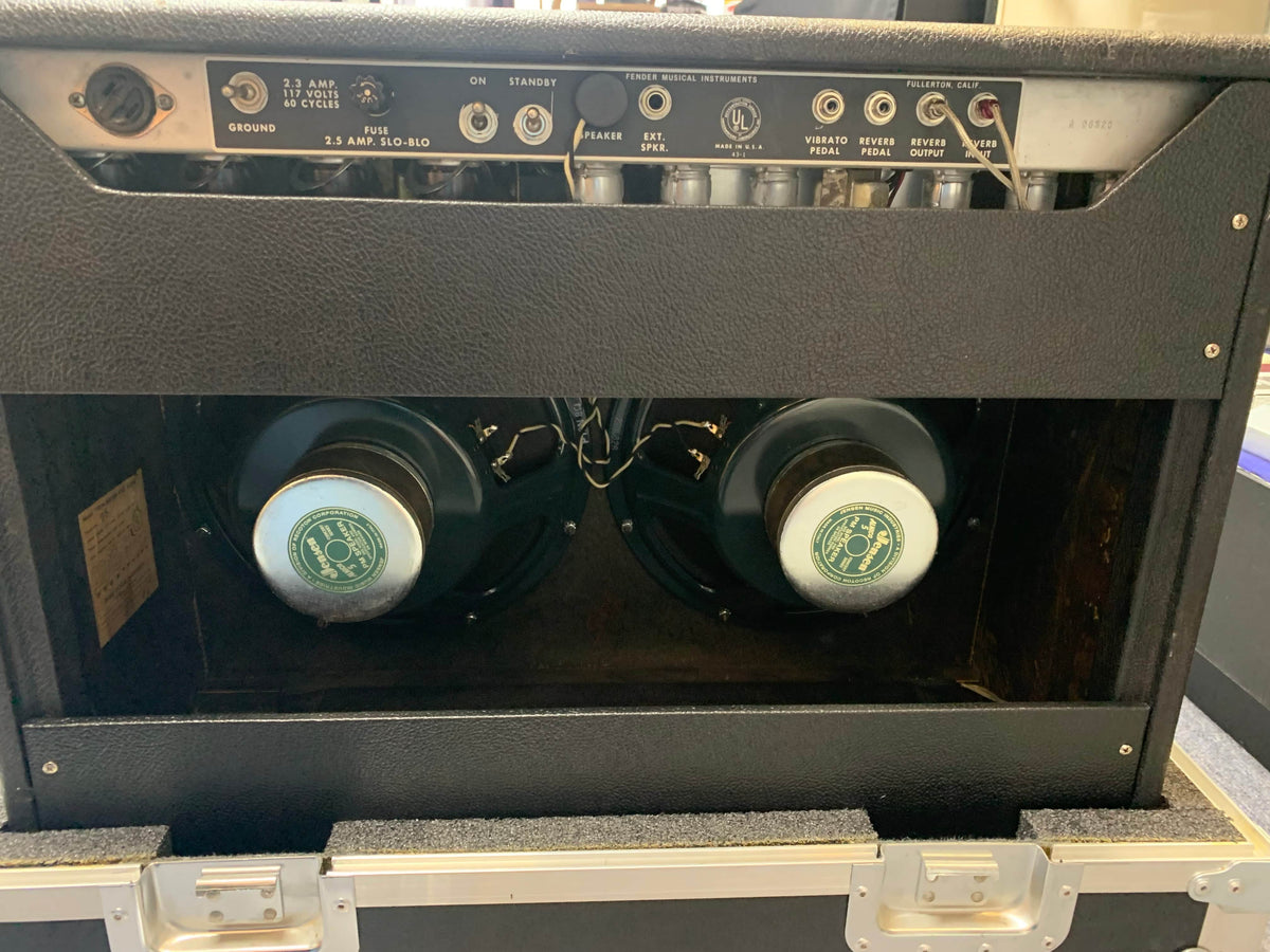 The back of a 1966 Fender Twin Reverb 2-Channel 85-Watt 2x12" Guitar Combo Amp is open, showing two large speakers and glowing vacuum tubes.