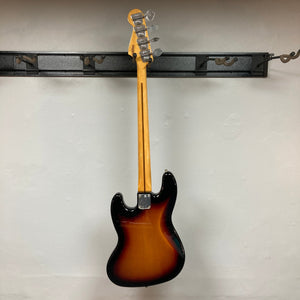 Fender Vintera '70s Jazz Bass on wall hook, showcasing its vintage-style neck and pickups, includes gig bag for protection.