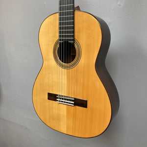Giambattista G8 Natural Used classical guitar by Jean-Baptiste Castelluccia, featuring detailed craftsmanship with visible strings and body contours, displayed on a wall.