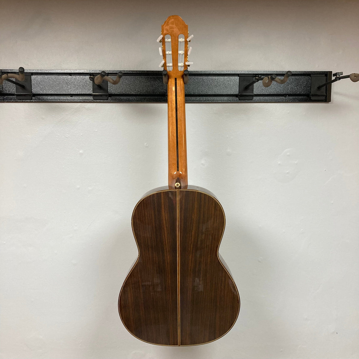 Giambattista G8 Natural Used guitar hanging on a wall, showcasing its elegant craftsmanship and detailed rosette, suitable for classical music enthusiasts.
