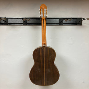 Giambattista G8 Natural Used guitar hanging on a wall, showcasing its elegant craftsmanship and detailed rosette, suitable for classical music enthusiasts.