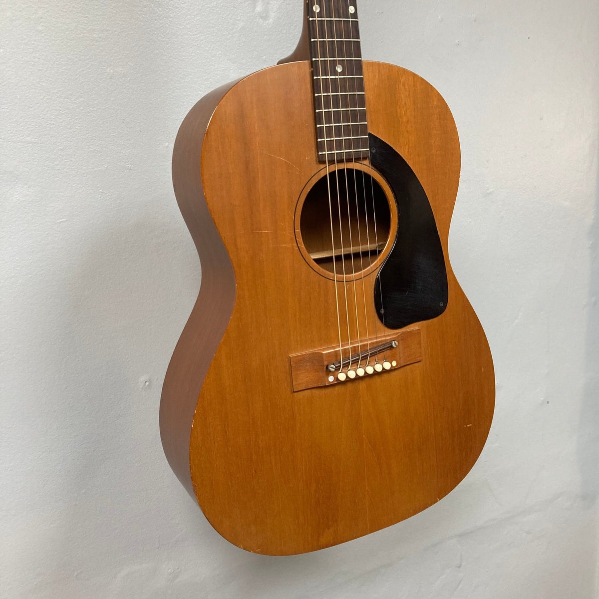 Gibson B-15 1967 - 1969 Natural acoustic guitar displayed on a wall, showcasing its solid mahogany body and neck. Close-up images highlight wear due to age.
