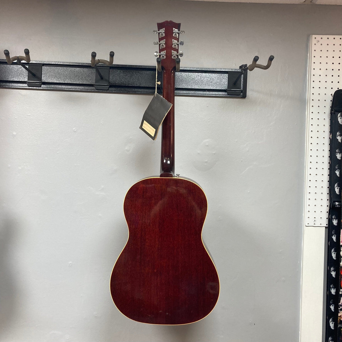 Gibson B-25 Acoustic Guitar Natural 1968 hanging on a wall, showcasing distinctive vintage checking and craftsmanship.