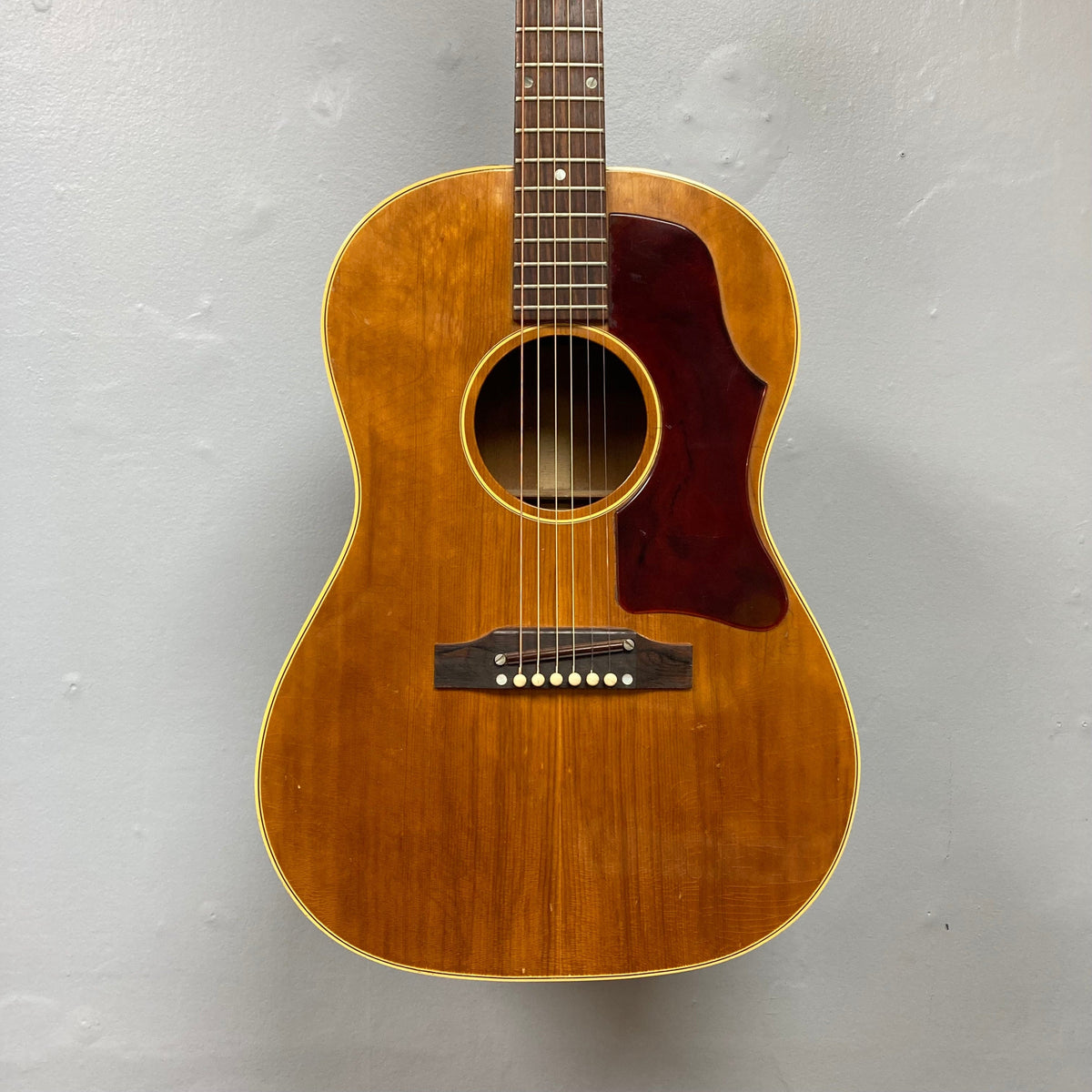 Gibson B-25 Acoustic Guitar Natural 1968, displayed on a wall, showcasing vintage checking and crafted in Kalamazoo.
