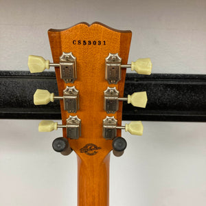Rear view of a Gibson Custom Shop Class 5 Les Paul headstock with six tuning pegs, serial number CS58031, and the Gibson Custom Shop logo engraved on flame maple wood.