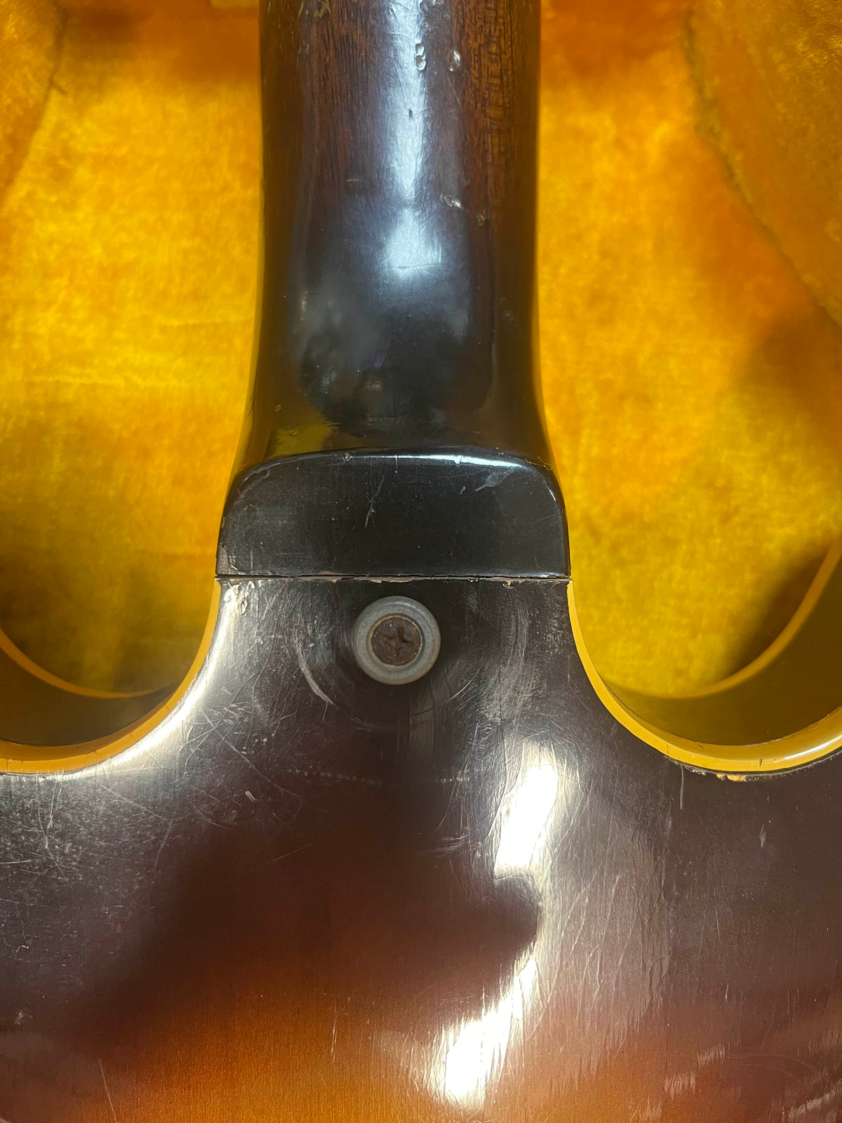 Close-up of the neck joint on a Gibson ES-335TD-12 1968 Sunburst, showing a screw and visible scratches on the finish, with a yellow background. Includes case.