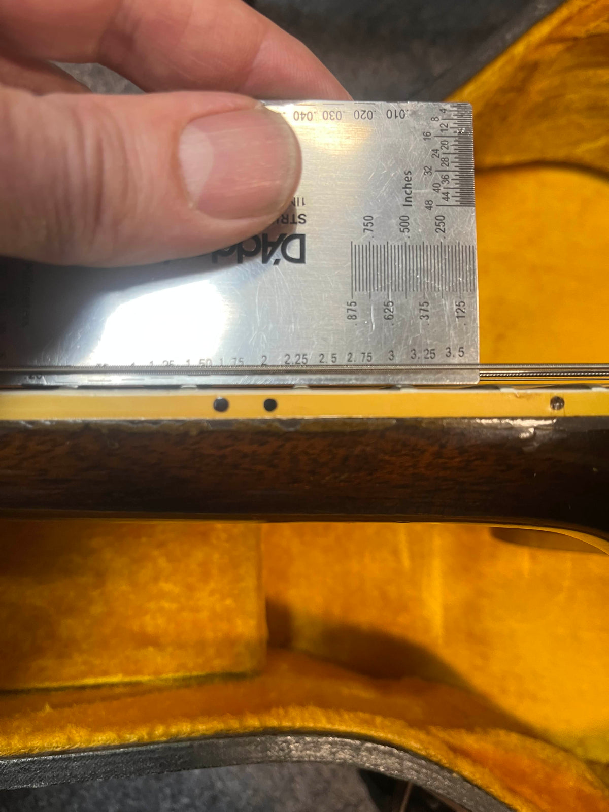 A metal ruler checks the frets of a Gibson ES-335TD-12 1968 Sunburst guitar, which rests in its yellow plush-lined Gibson case.
