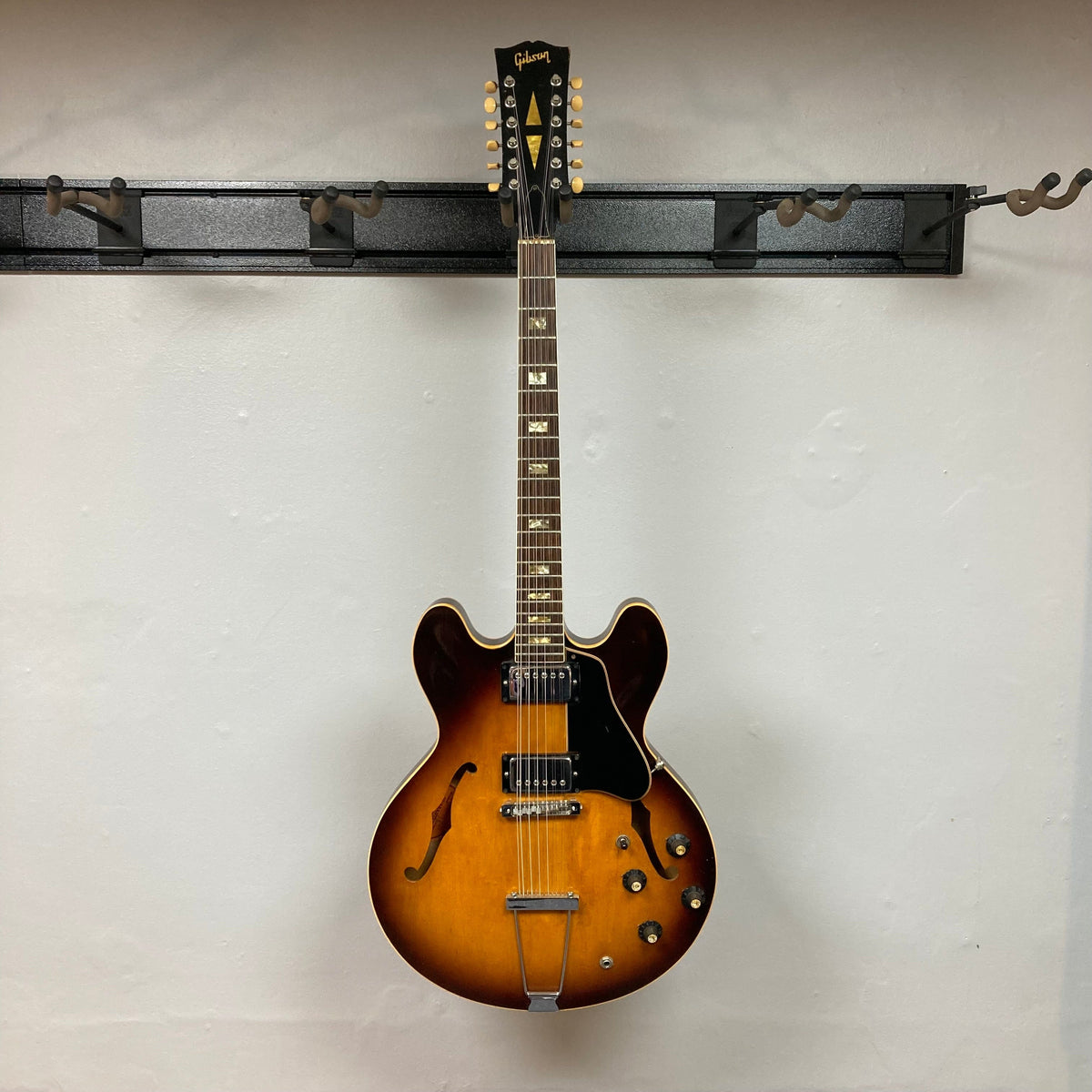 Gibson ES-335TD-12 1968 Sunburst guitar on a hook, showcasing its double-cutaway design and semi-hollow body.