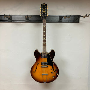 Gibson ES-335TD-12 1968 Sunburst guitar on a hook, showcasing its double-cutaway design and semi-hollow body.