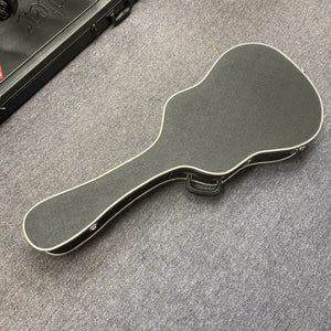 A closed Gibson J-45 1957 (Serial U-8664-1) vintage black guitar case with white trim rests on a gray carpeted floor.