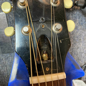 Close-up of the Gibson J-45 1957 (Serial U-8664-1) headstock, highlighting tuning pegs, strings, truss rod access cavity, and part of a blue guitar support—iconic vintage style by Gibson.