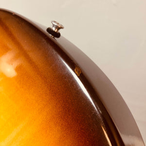 Close-up of a Gibson Les Paul Junior 1957 Sunburst body, highlighting a small chip near the edge and the metal strap button—classic details from this iconic Gibson electric guitar.