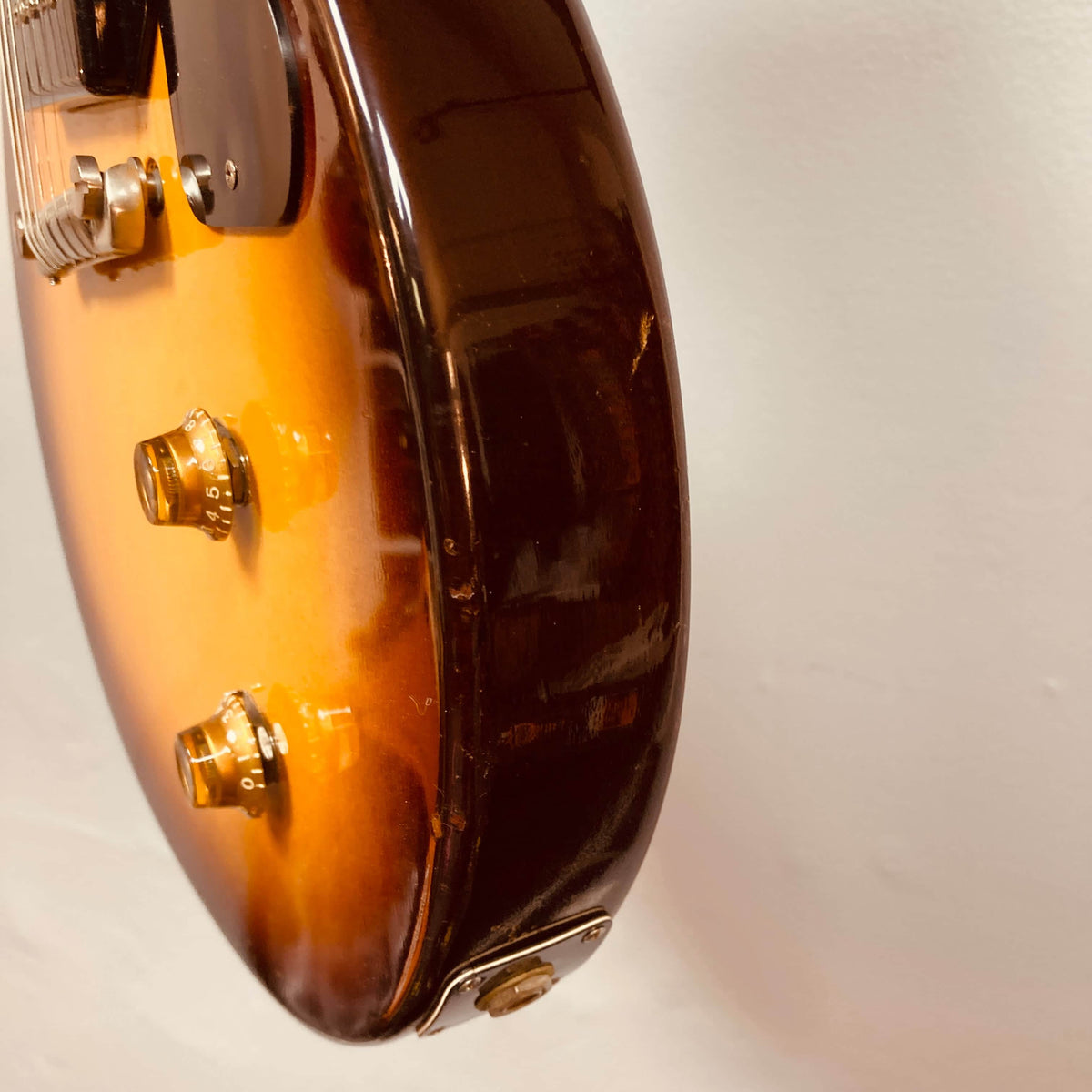 Close-up of a Gibson Les Paul Junior 1957 Sunburst electric guitar body by Gibson, featuring two control knobs, input jack, and minor side scratches against a plain background.