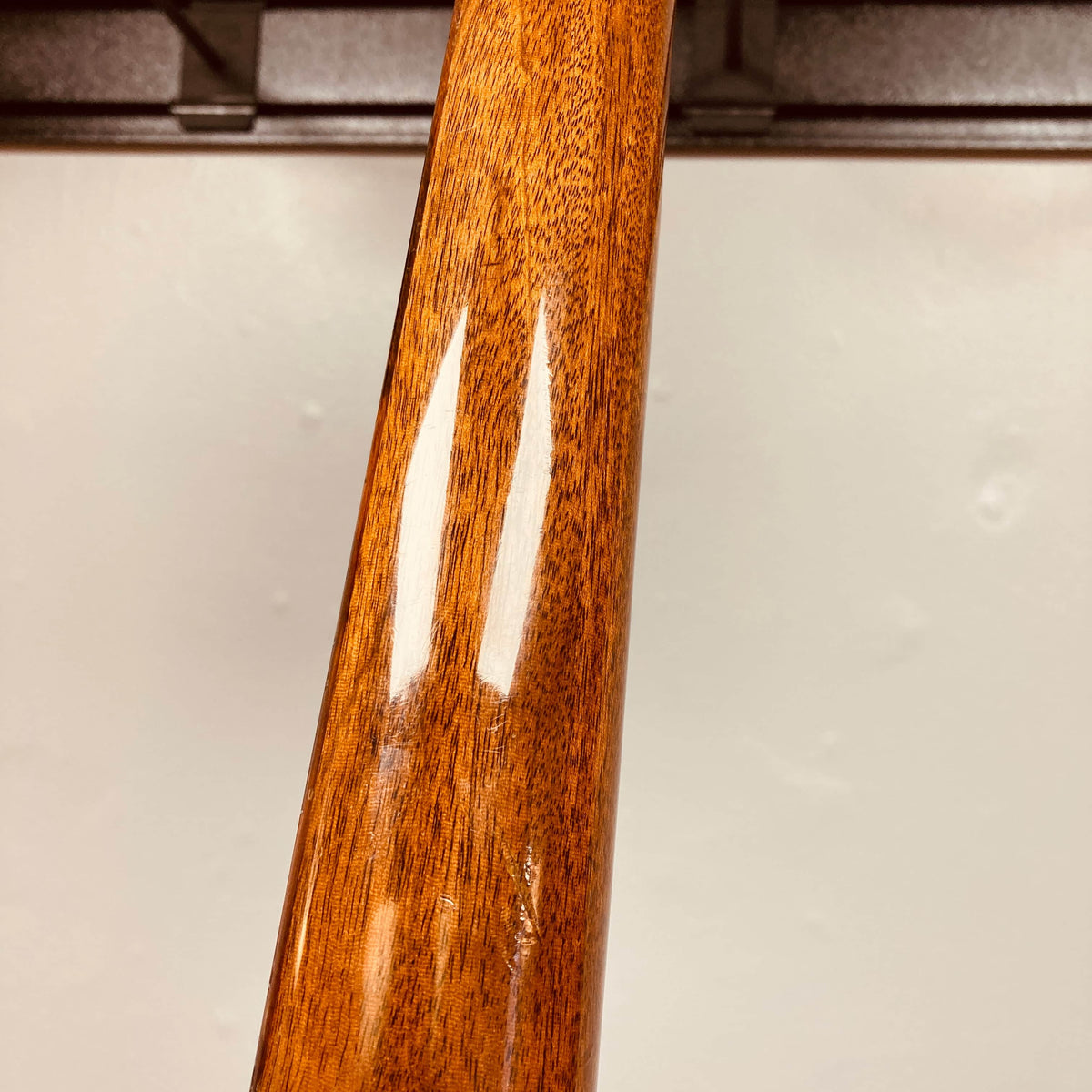 Close-up of a polished Gibson Les Paul Junior 1957 Sunburst guitar neck by Gibson, with natural grain visible and reflections against an off-white background, emphasizing the vintage allure of this classic electric guitar.
