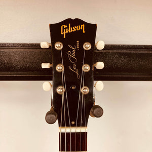 Close-up of a Gibson Les Paul Junior 1957 Sunburst headstock, showing tuning pegs and the Gibson logo against a neutral background.