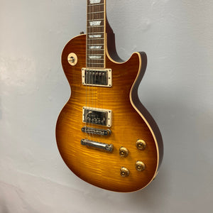 Gibson Les Paul Standard Premium Plus 2003 Ice Tea Burst electric guitar with flamed maple top and Burstbucker Pro pickups displayed on a wall.