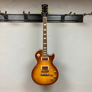 Gibson Les Paul Standard Premium Plus 2003 Ice Tea Burst, hanging on a wall, showcasing its flamed maple top and sleek design.