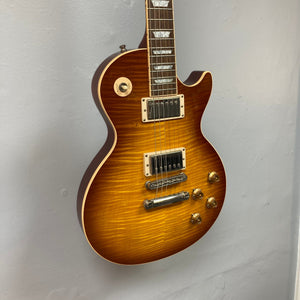 Gibson Les Paul Standard Premium Plus 2003 Ice Tea Burst electric guitar with flamed maple top and Burstbucker Pro pickups displayed on a wall.