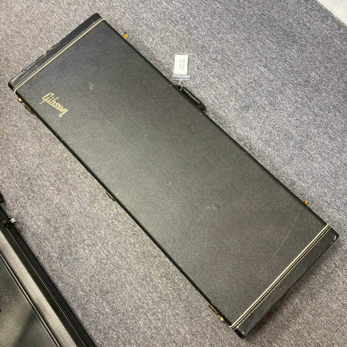 A black rectangular hard case with the Gibson logo, from Guitars on Main, holds a Gibson RD Artist 1977–1982 guitar and rests closed on a gray carpeted floor.