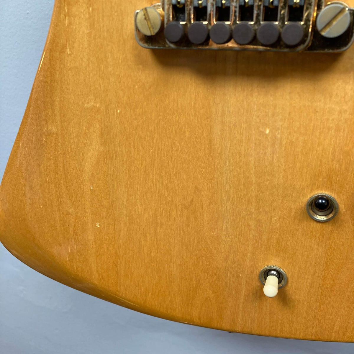 Close-up of a Gibson RD Artist 1977-1982 electric guitar body from Guitars on Main, highlighting the bridge, input jack, and toggle switch on a light wood finish—an iconic collectible with case included.