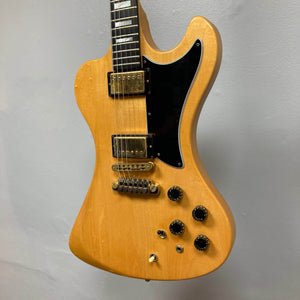 The Gibson RD Artist 1977-1982 w/Case by Guitars on Main features a natural wood finish, black pickguard, dual humbuckers, four knobs, and a toggle switch—photographed against a plain light gray wall.