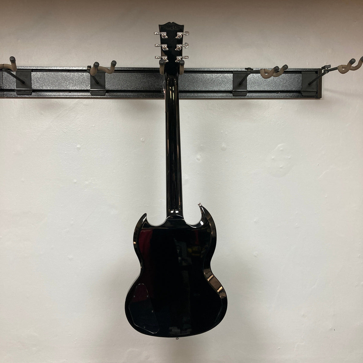 Gibson SG Modern Exclusive Dark Purple Burst Blem displayed on a wall, showcasing its sleek design and premium features, perfect for all guitar enthusiasts.