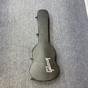 Black guitar case for the Gibson SG Modern Exclusive Dark Purple Burst Blem, positioned on a grey carpet.
