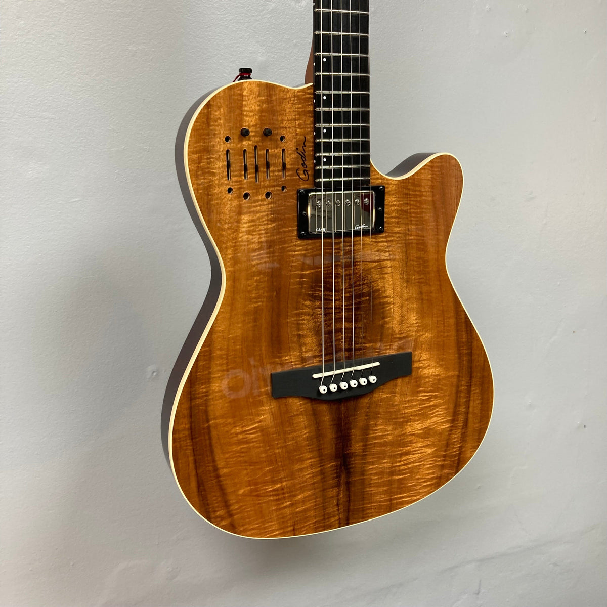 Close-up of the Godin A6 Ultra Koa Extreme SF guitar, showcasing its strings and neck with advanced preamp controls for versatile sound customization.