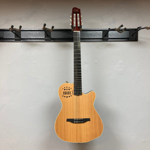 Godin Ltd Multiac ACS Cedar Matte SG w/GigBag hanging on a wall, showcasing its sleek design and classical guitar elements with solid body features.
