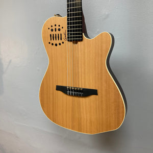 Godin Ltd Multiac ACS Cedar Matte SG guitar displayed on a wall, highlighting its classical design and advanced synth access features.