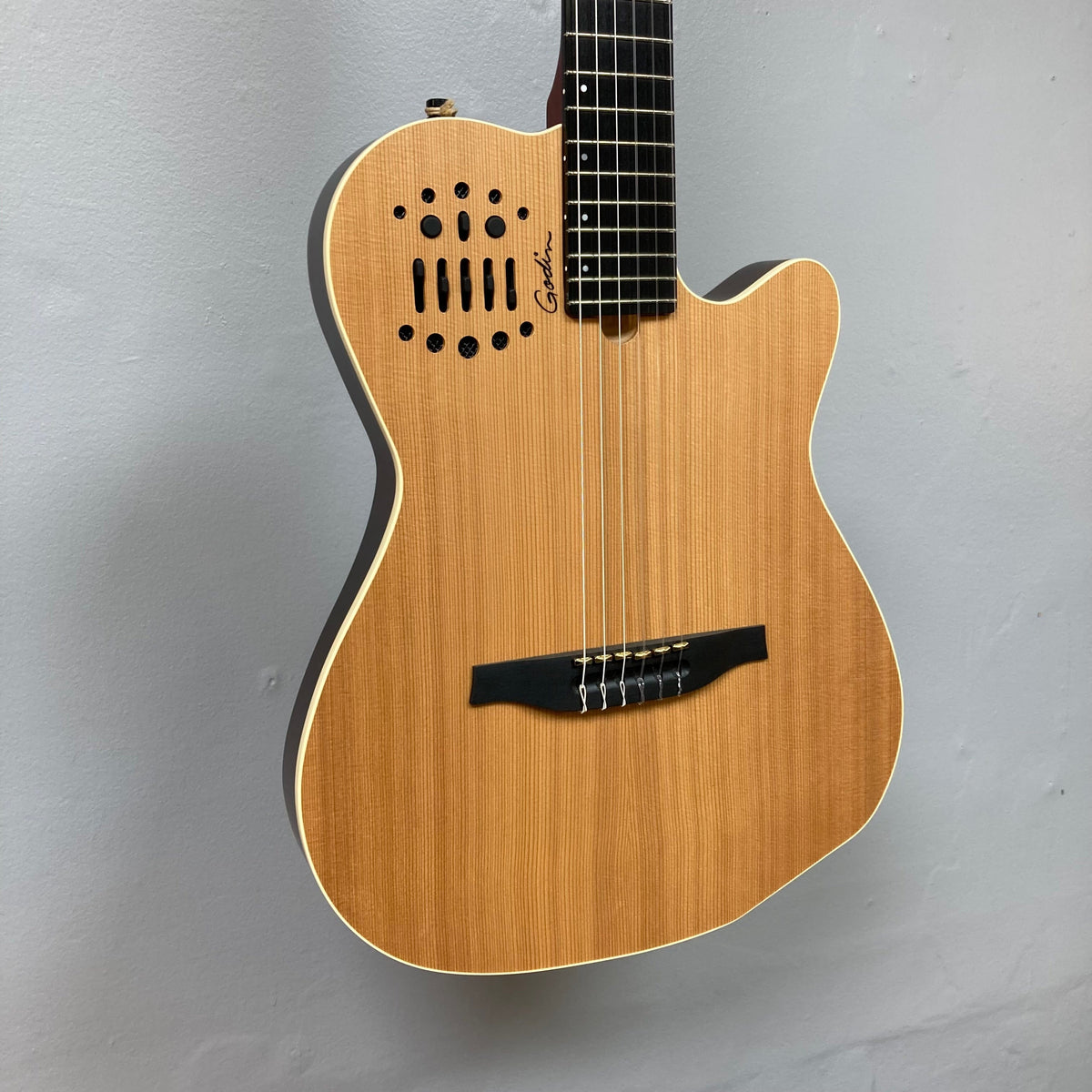 Godin Ltd Multiac ACS Cedar Matte SG w/GigBag displayed on a wall, showcasing its cedar top and comfortable neck design.