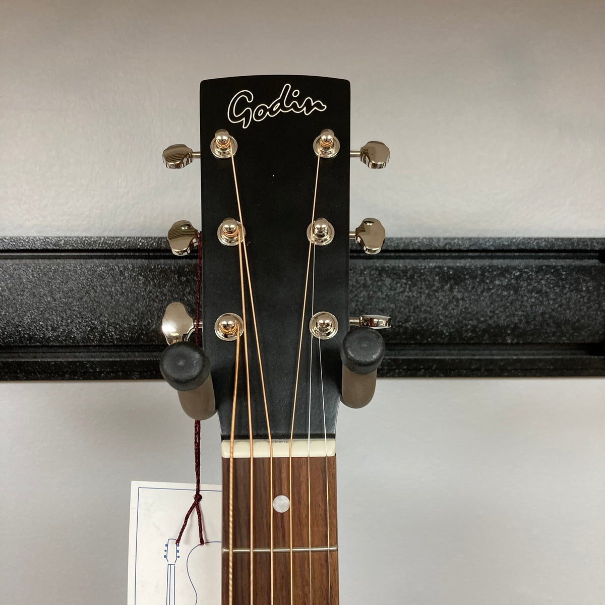 Godin Mahogany Folk Rustic Burst A/E guitar on a stand with visible strings and knobs.