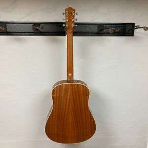 Godin Metropolis Natural RN GT EQ acoustic guitar mounted on a wall, showcasing its mahogany body, spruce top, and distinctive headstock.