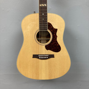 Godin Metropolis Natural RN GT EQ acoustic guitar showcasing its sleek design, smooth neck, and detailed components like the unique pickguard, headstock plate, and fretboard inlay.
