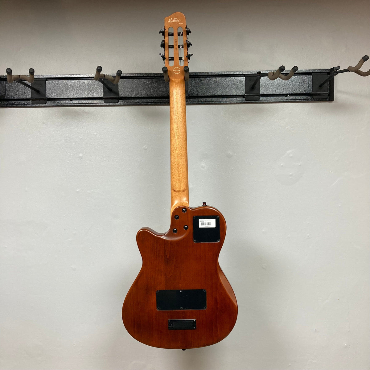 Godin Prototype Ltd Mundial Dark Cedar w/GigBag hanging on a wall hook, showcasing its elegant design and craftsmanship.