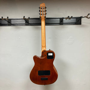 Godin Prototype Ltd Mundial Dark Cedar w/GigBag hanging on a wall hook, showcasing its elegant design and craftsmanship.