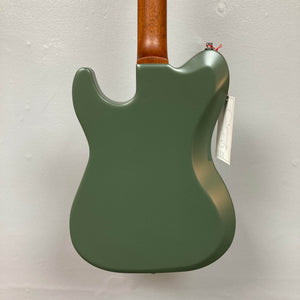 Back view of a Godin Radium Matte Green electric guitar with a brown neck and Godin Zebra Humbuckers, hanging on a plain white wall; a white tag is attached near the neck joint.