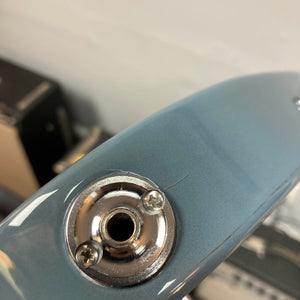 Close-up of the input jack on a metallic blue Godin Session T-Pro with Bag by Godin, featuring an H-S-S pickup configuration and a slight paint crack near the mounting plate.