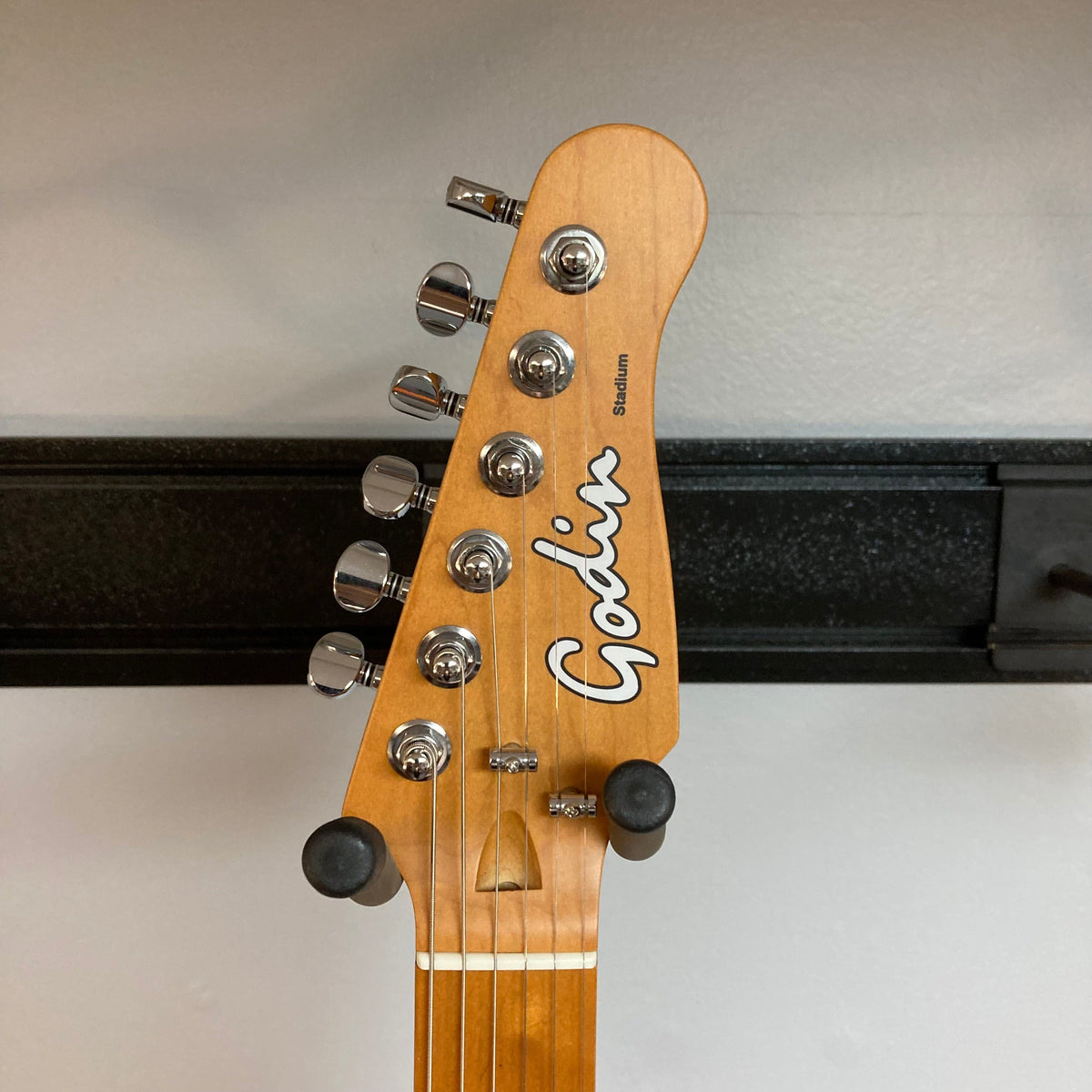 Godin Stadium Pro Sunset Burst MN w/GigBag Electric Guitar featuring a close-up of its headstock, tuning knobs, and neck, highlighting its precise craftsmanship.